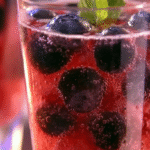 Berry spark fizz drink with fresh berries, ice, and mint served in a tall glass