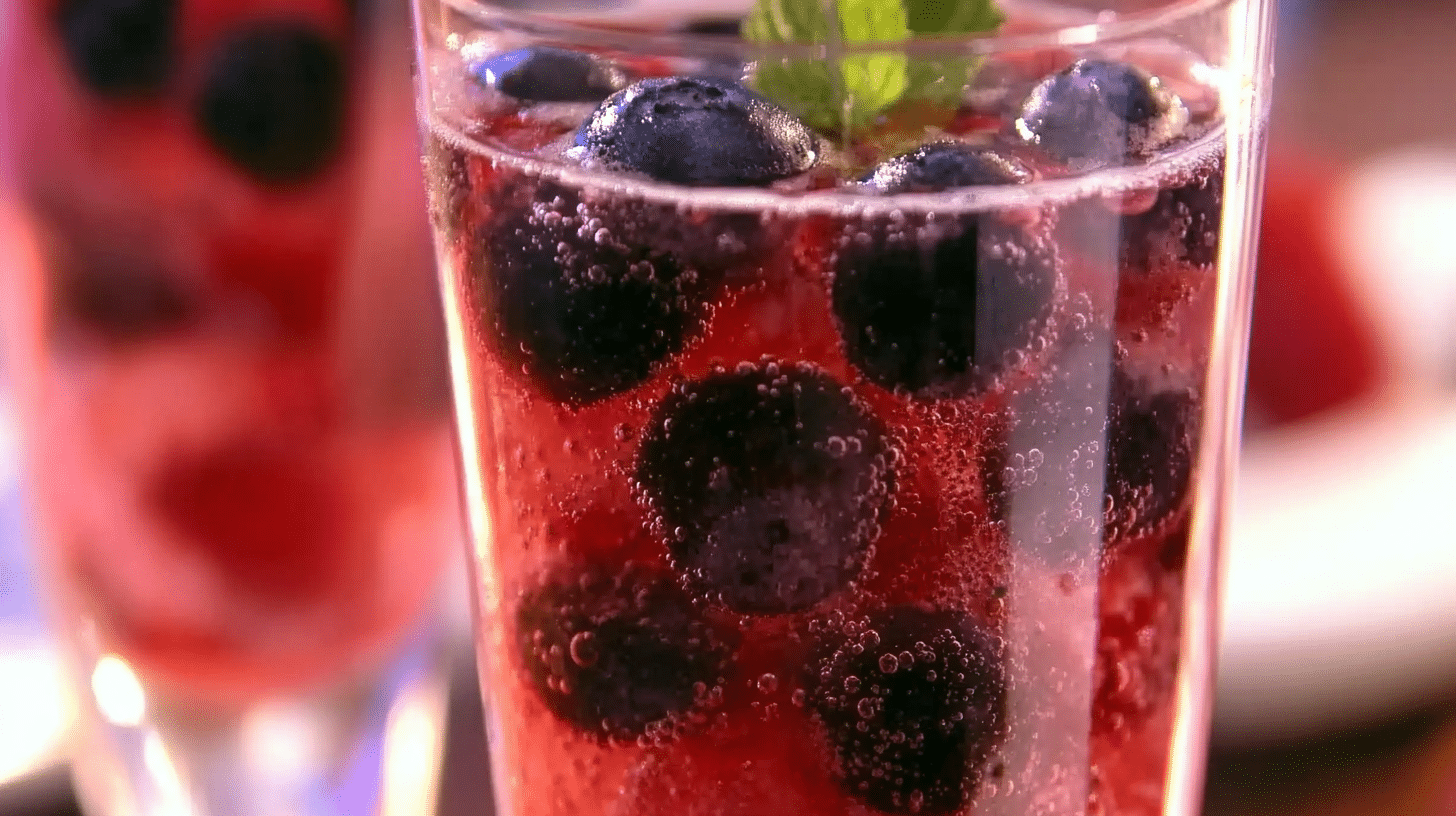 Berry spark fizz drink with fresh berries, ice, and mint served in a tall glass