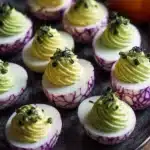 Halloween-themed deviled eggs with spooky decorations on a platter.