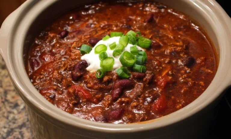 A bowl of delicious slow cooker chili topped with cheese and cilantro.