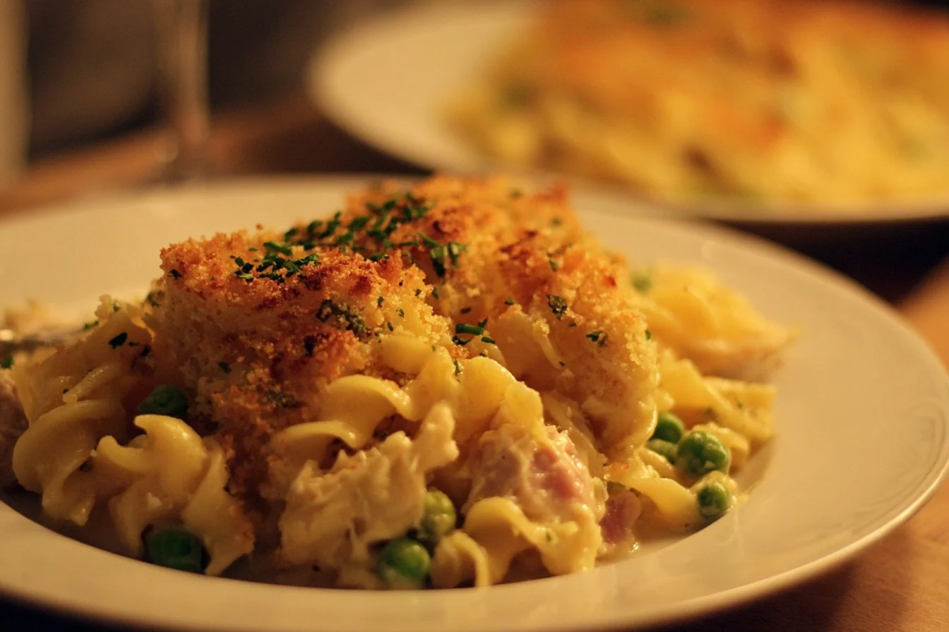 A homemade Tuna Noodle Casserole served in a baking dish, garnished with herbs.