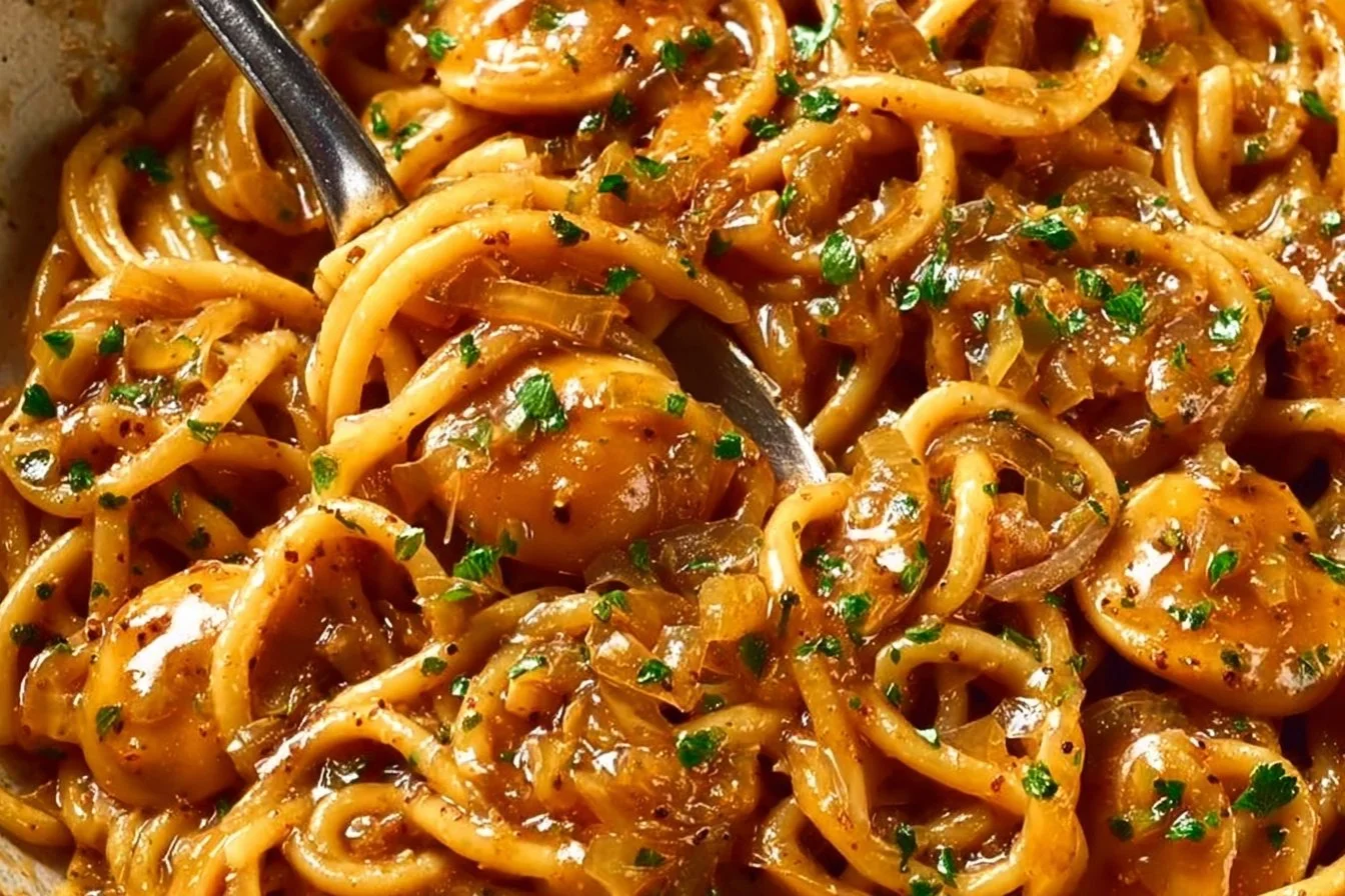 Bowl of French Onion Pasta topped with melted cheese and caramelized onions.