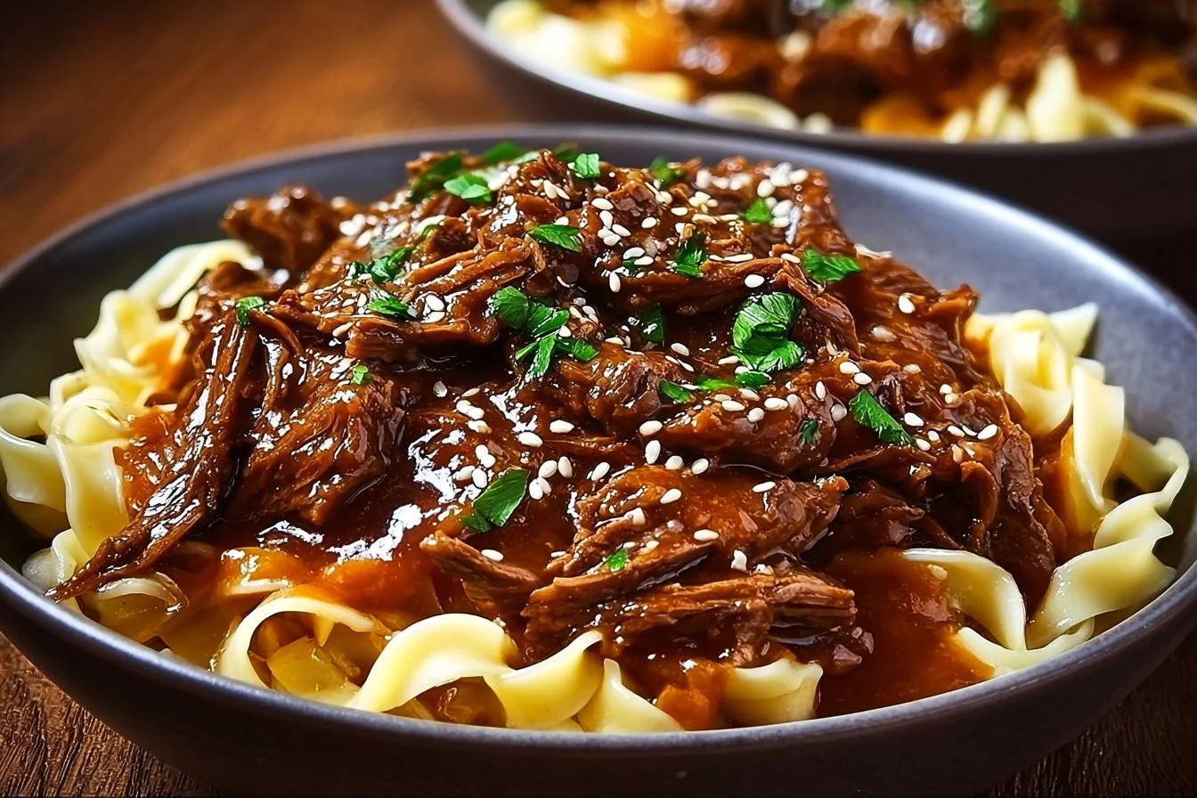A bowl of Korean beef noodles garnished with vegetables and herbs.
