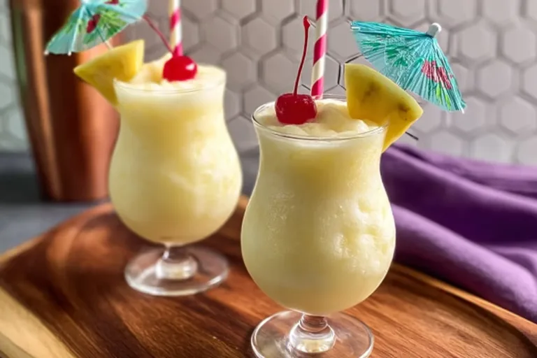 Colorful slushie cocktails garnished with fruits in stylish glasses.