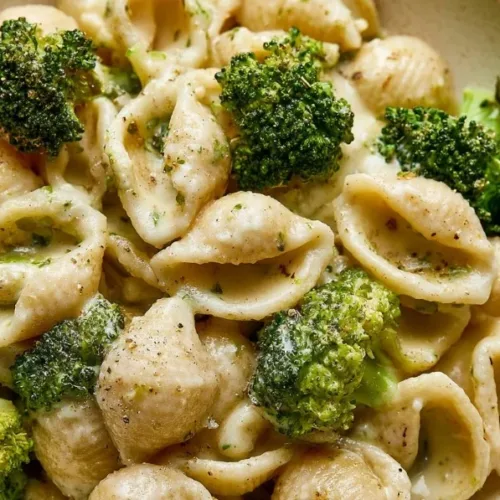 Delicious plate of broccoli pasta garnished with herbs.