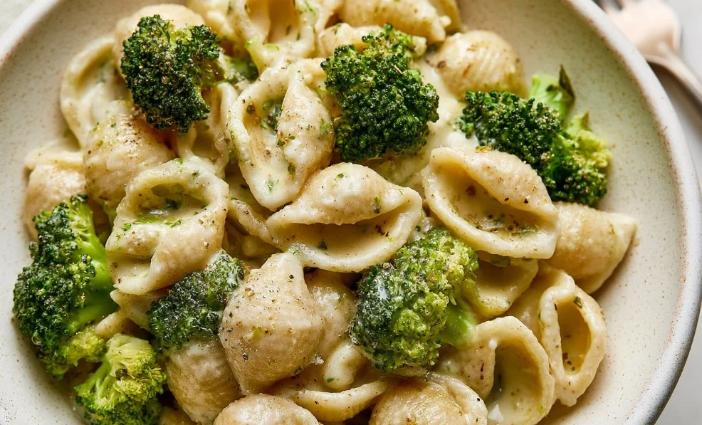 Delicious plate of broccoli pasta garnished with herbs.